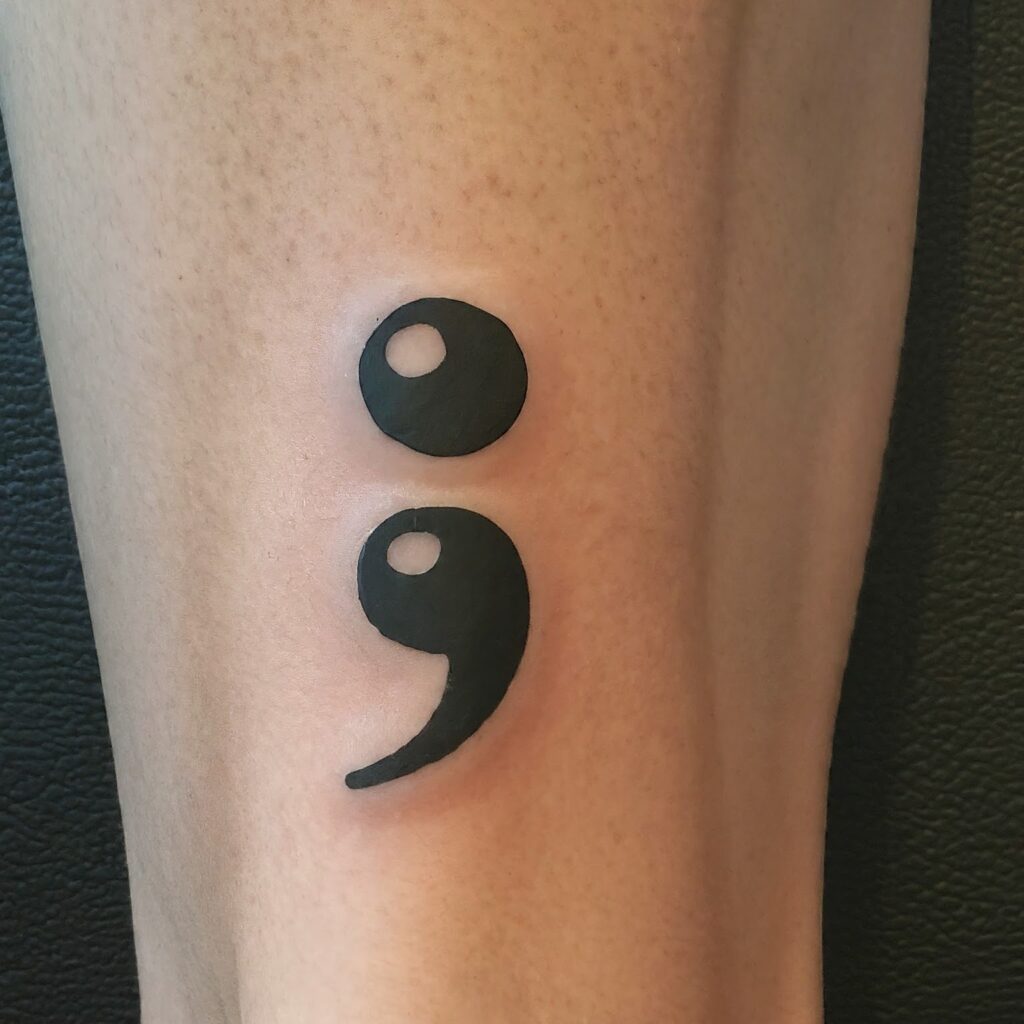 A minimalist line art illustration of a semicolon tattoo on a person's ankle.